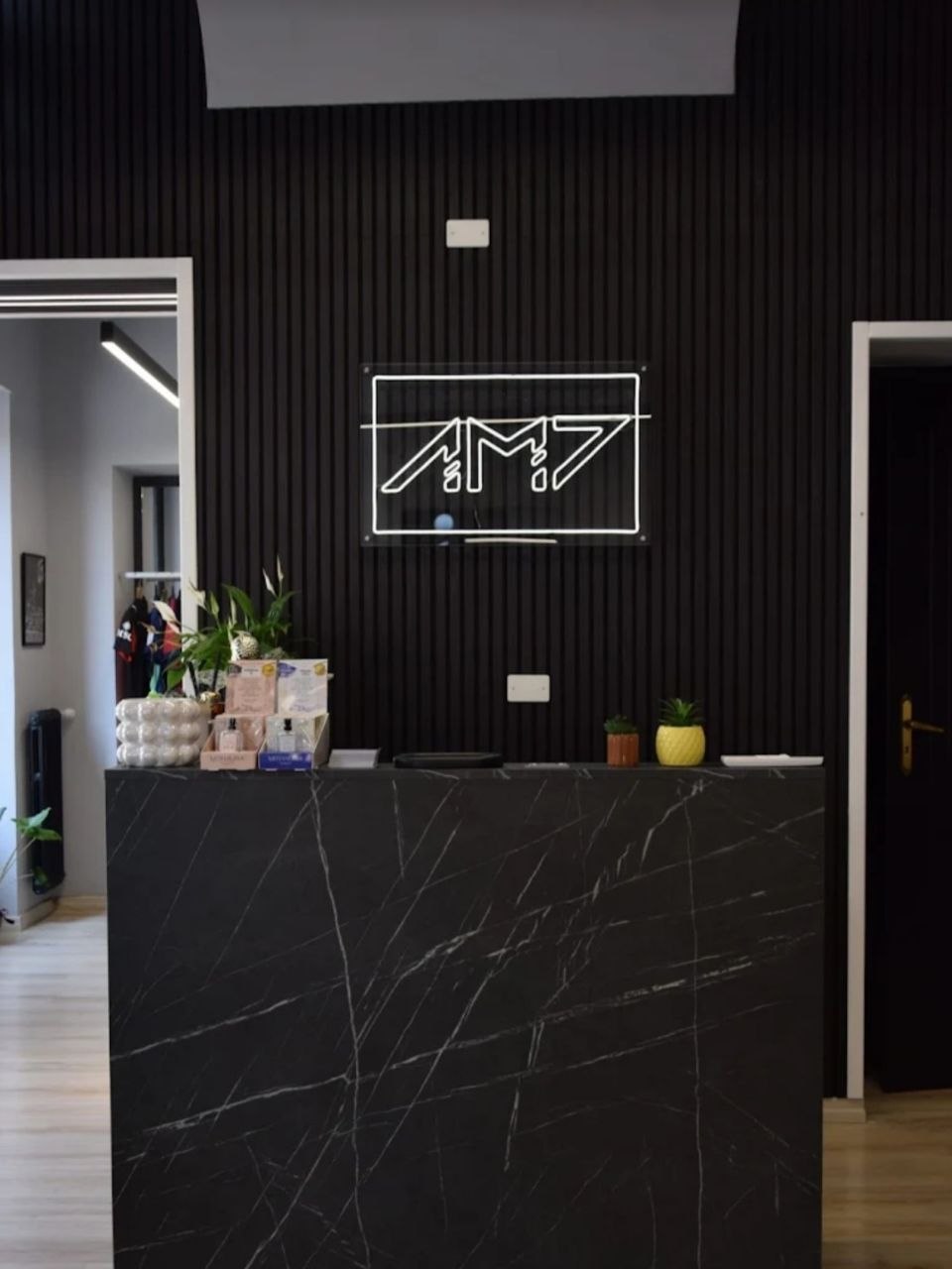 Bancone e logo luminoso all'interno di AM7 Barber